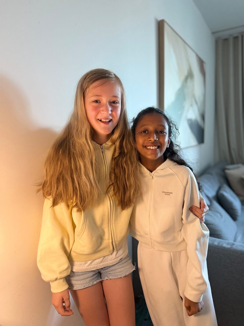 Sasha and Amaaya (Amy) smiling side by side, arm in arm.